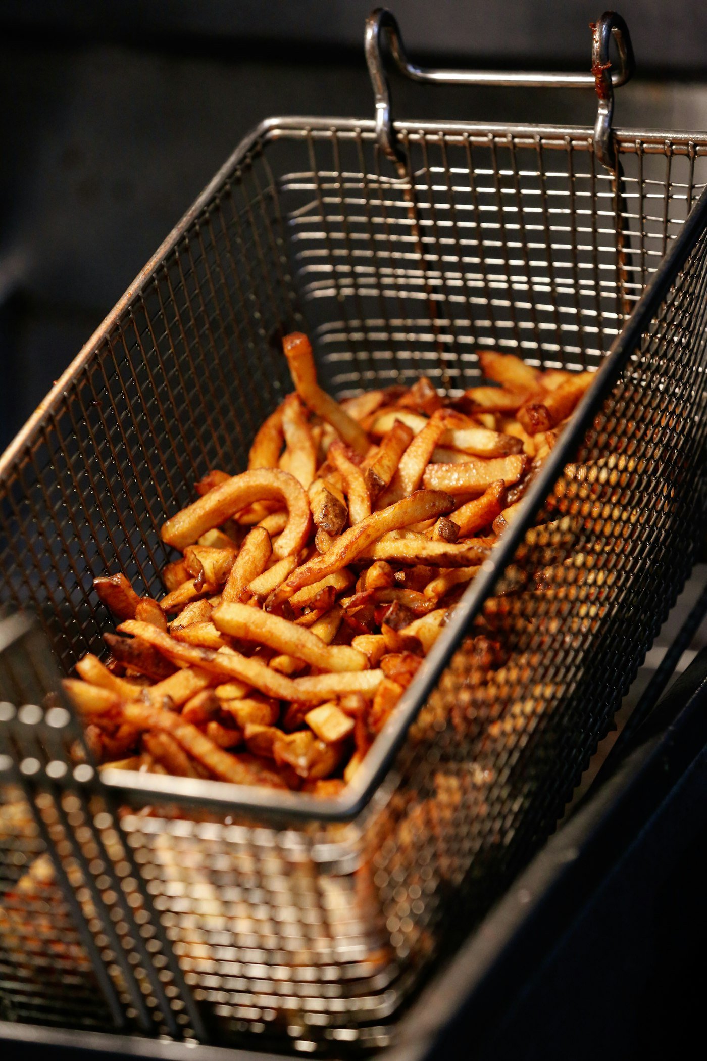 Papas fritas doradas y crocantes recién cocinadas en el canasto de una freidora de aire